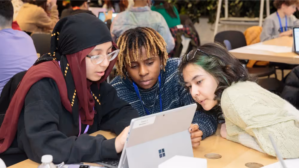 Three women looking at a laptop.