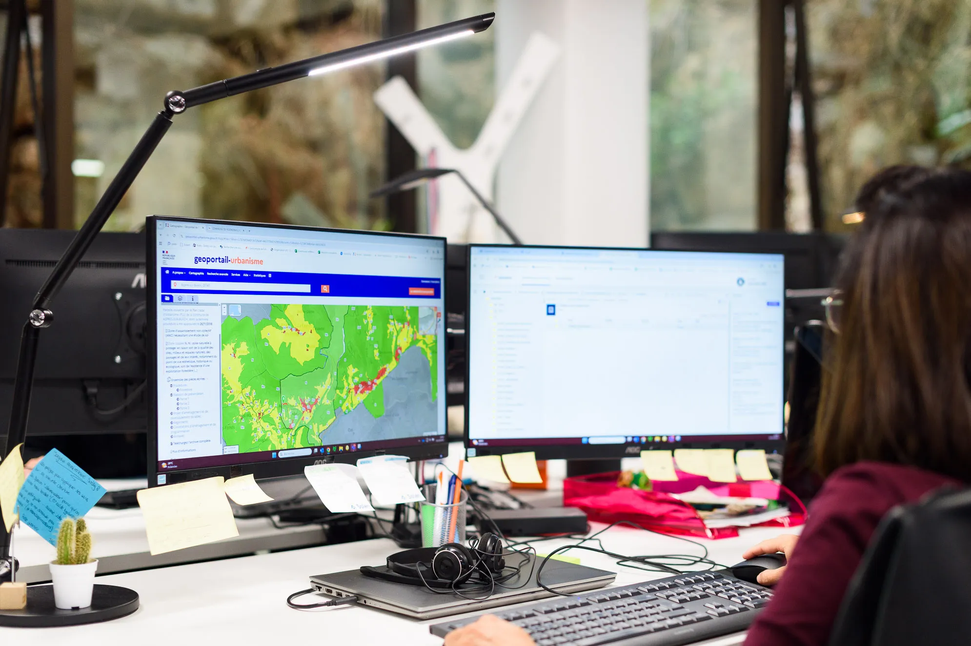 Experte Preventimmo travaillant sur double écran avec carte de risques dans un bureau moderne.