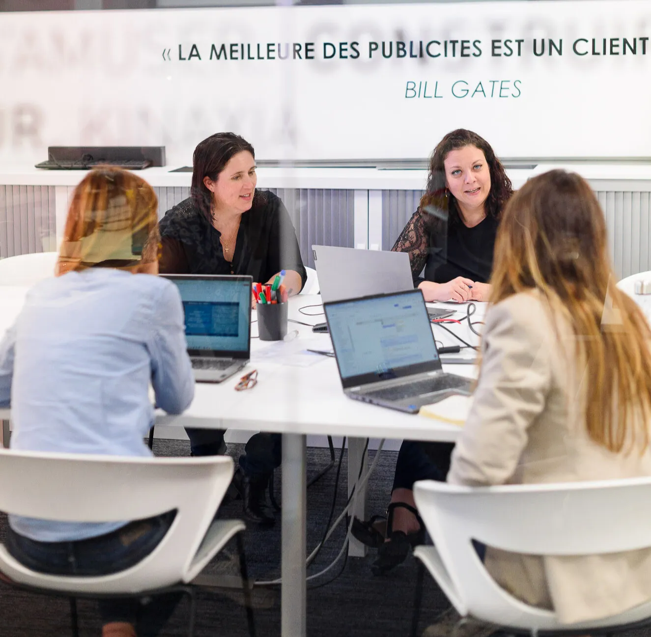Expertes Preventimmo autour d'une table avec des ordinateurs portables, discutant en réunion professionnelle.