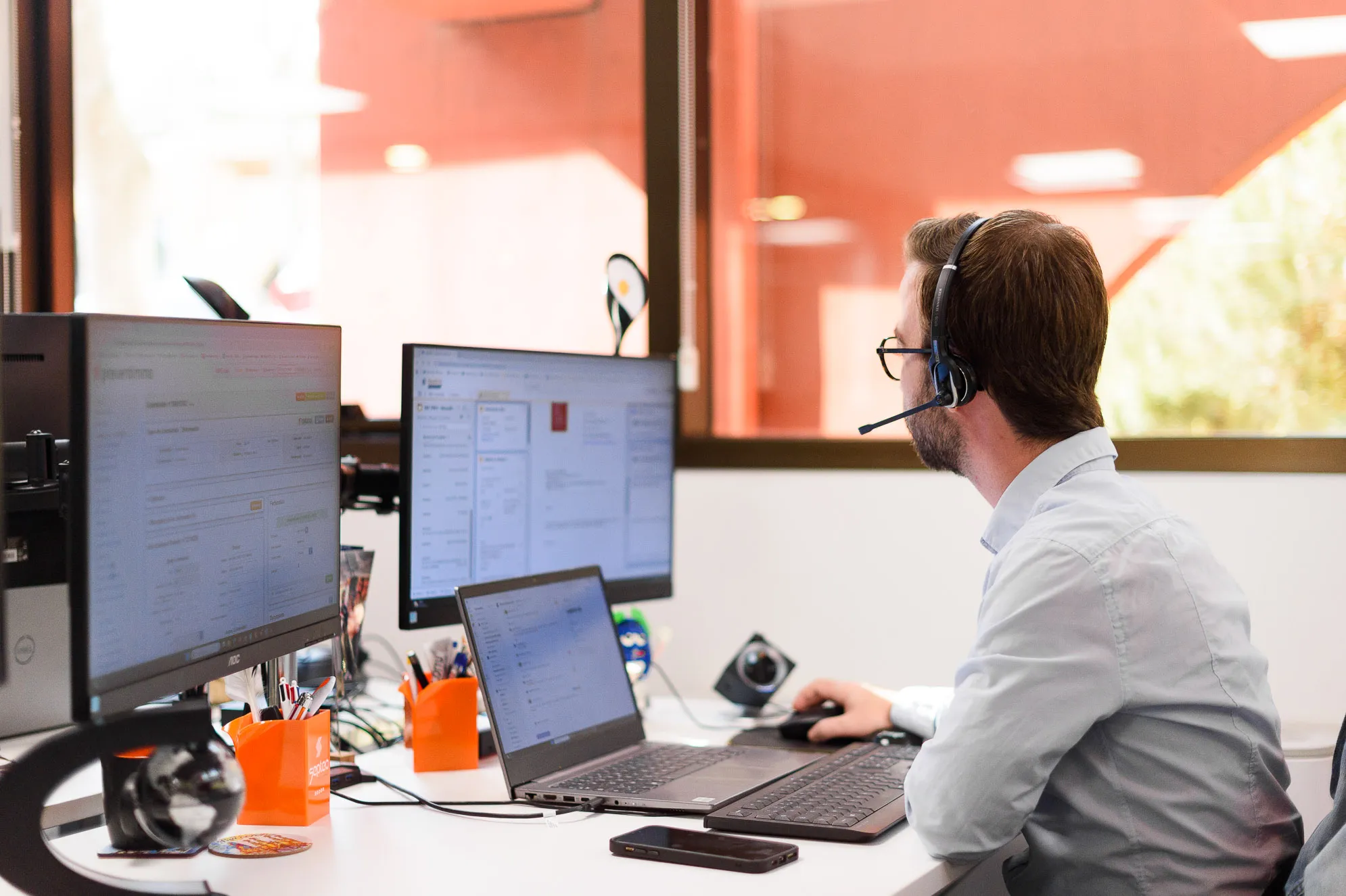 Homme support client Preventimmo avec un casque avec micro, travaillant sur ordinateur.