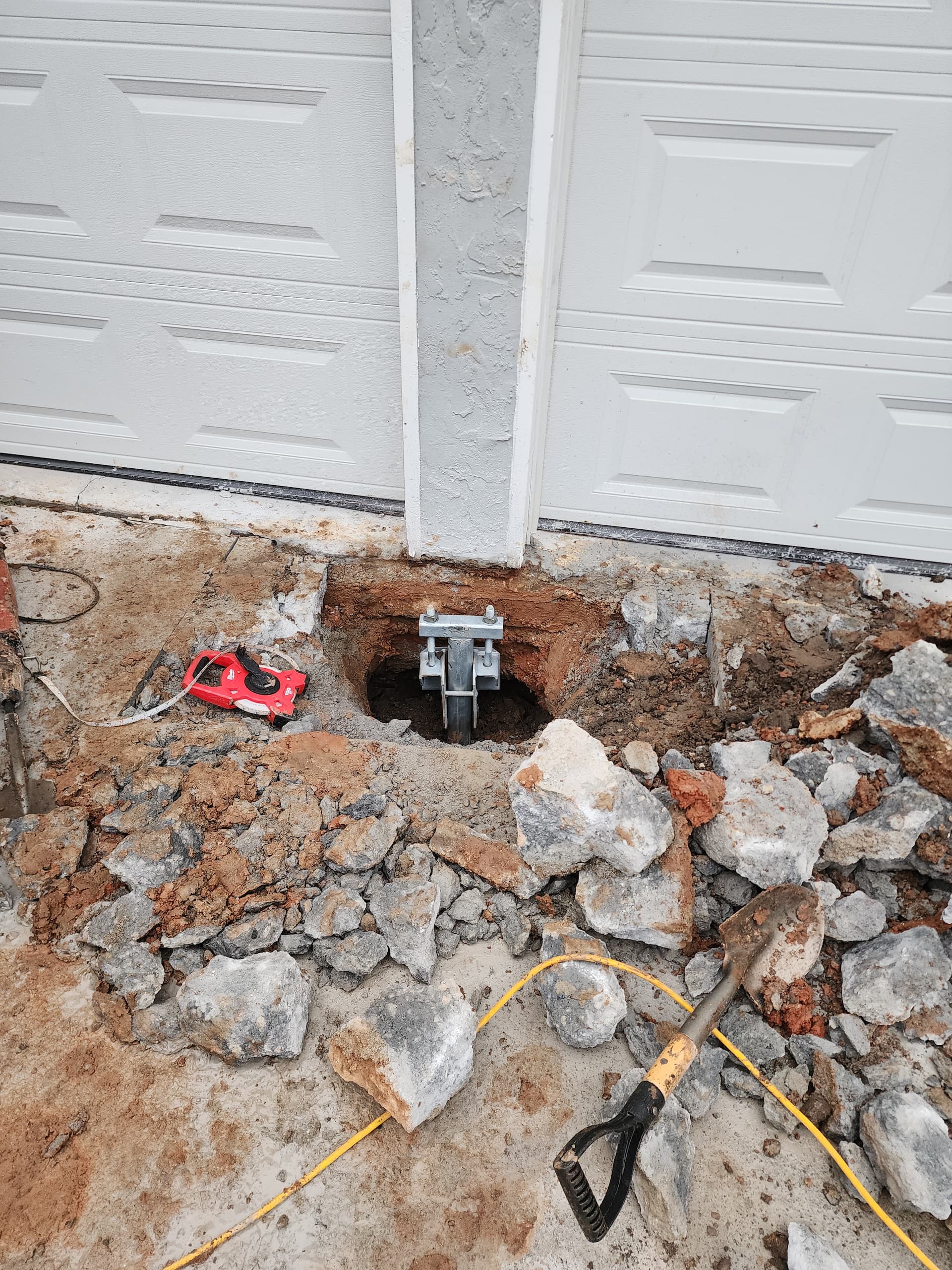 Worker installing helical pier for foundation waterproofing