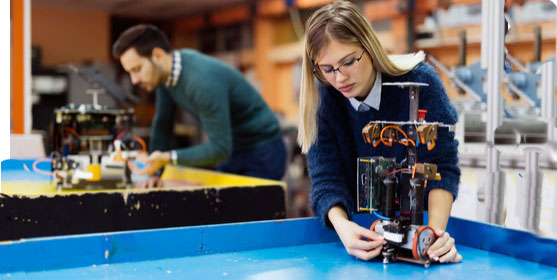 Une femme ingénieur qui assemble et teste un robot industriel pour le secteur de la Défense.