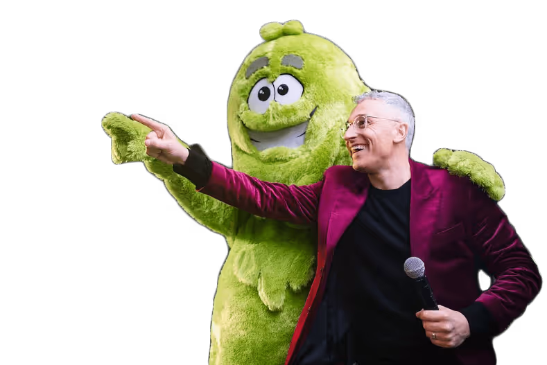 a man in a purple jacket holding a microphone and pointing at a person in a garment