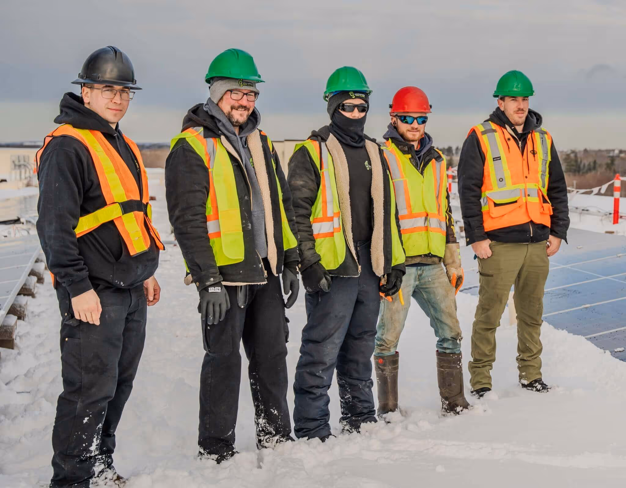 a group of men in safety vests and helmets standing in snow