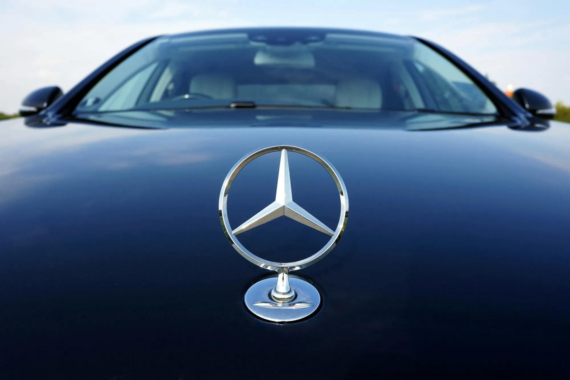 Le sigle Mercedes brille sur le capot d’un véhicule de luxe utilisé pour les services de chauffeur privé à Cannes.