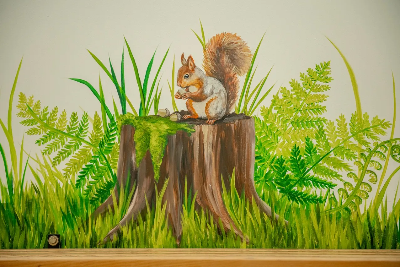 Squirrel nursery art. Hand-painted squirrel on a tree stump with ferns and grass, perfect for a woodland-themed baby room.