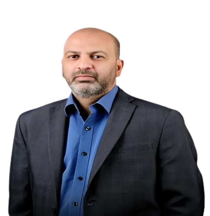 Man with a beard wearing a dark suit jacket and a blue shirt, posing against a black background.