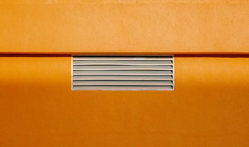 A close up of a yellow wall with a window.