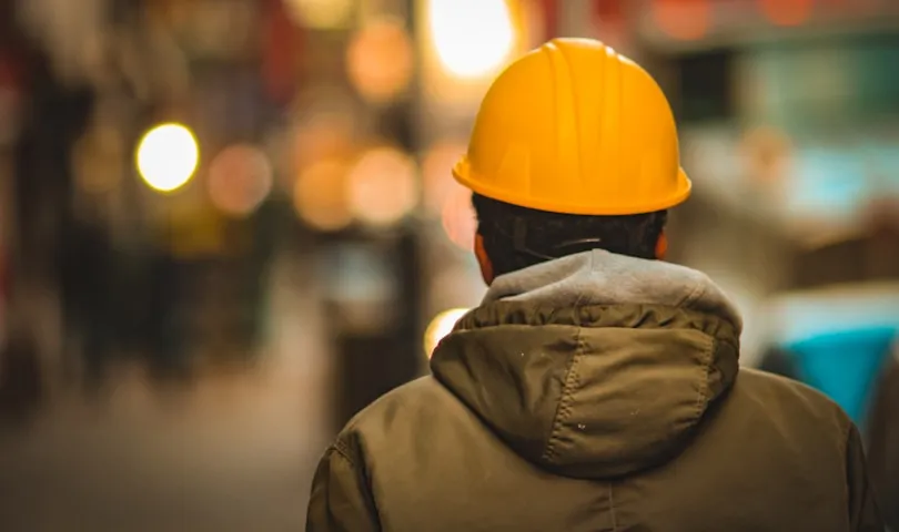 A man wearing a hard hat walking down a street.