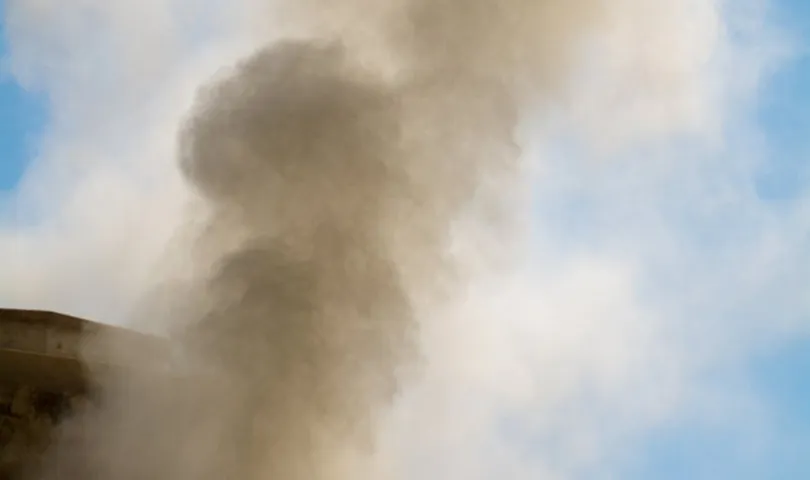 Smoke billows from the top of a building.