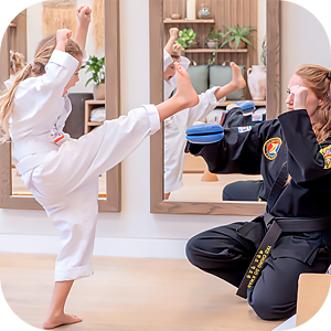 Young girl in white martial arts uniform practicing a kick towards a black padded target held by an instructor in a black martial arts uniform.