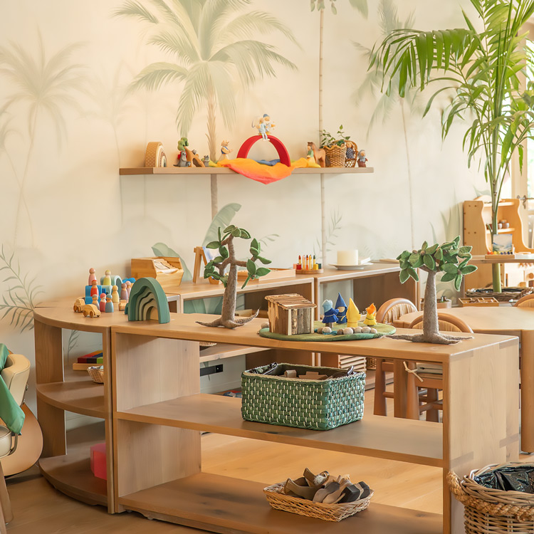 Bright children's playroom with wooden shelves displaying natural-themed toys, small figurines, and woven baskets, surrounded by wall murals of palm trees and indoor plants.