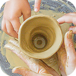 Hands shaping a clay pot on a pottery wheel, including an adult's and a child's hands.