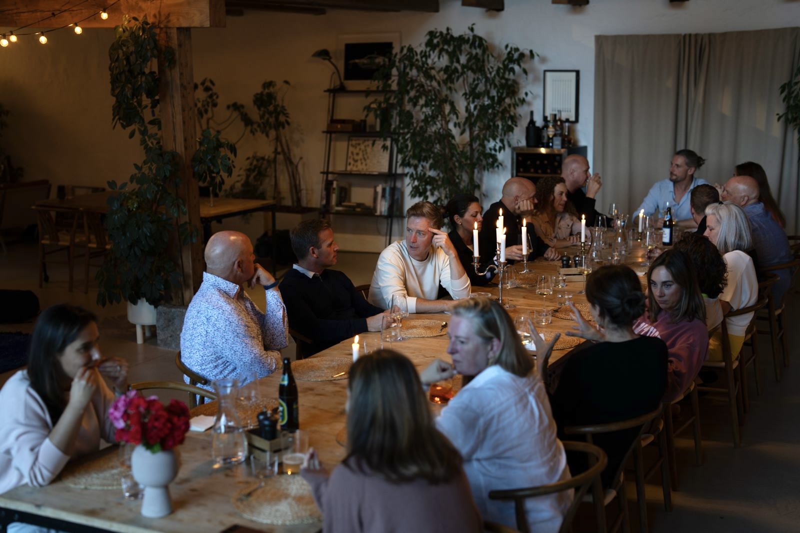 Long table dinner in a light-filled room, guests in conversation