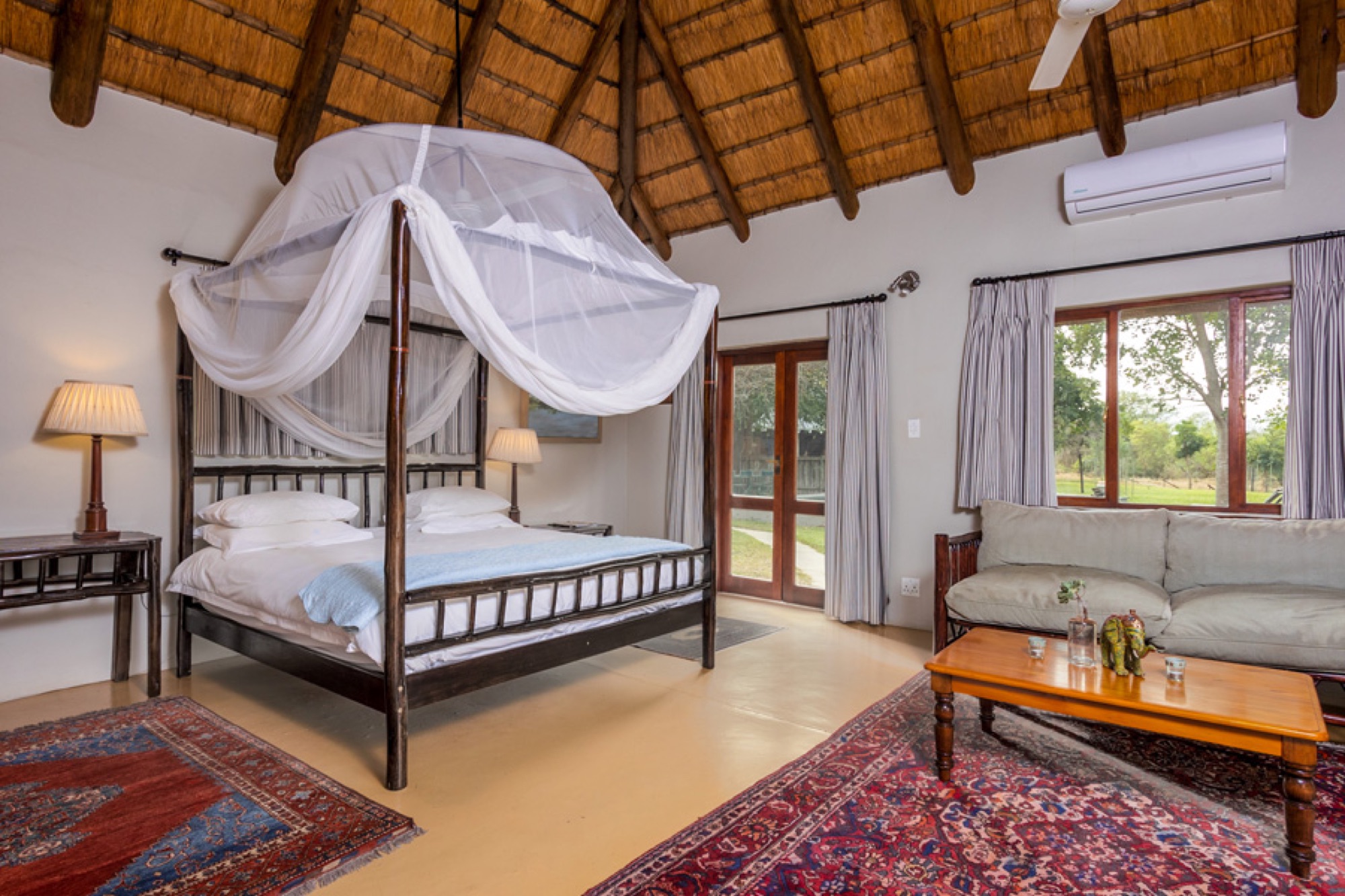A bedroom with a four-poster bed and mosquito net