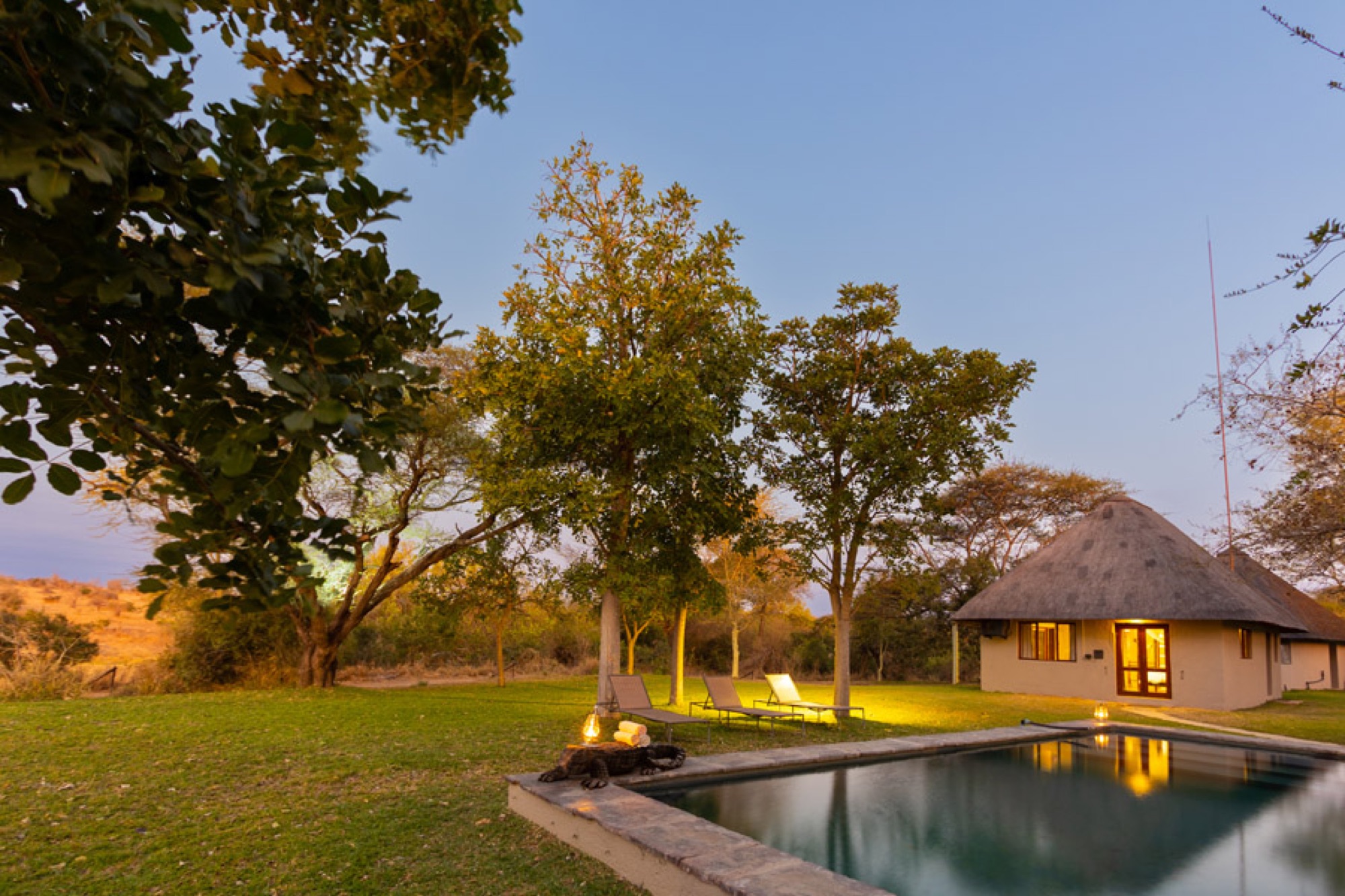 The lodge and pool at sunset with thatched roofs