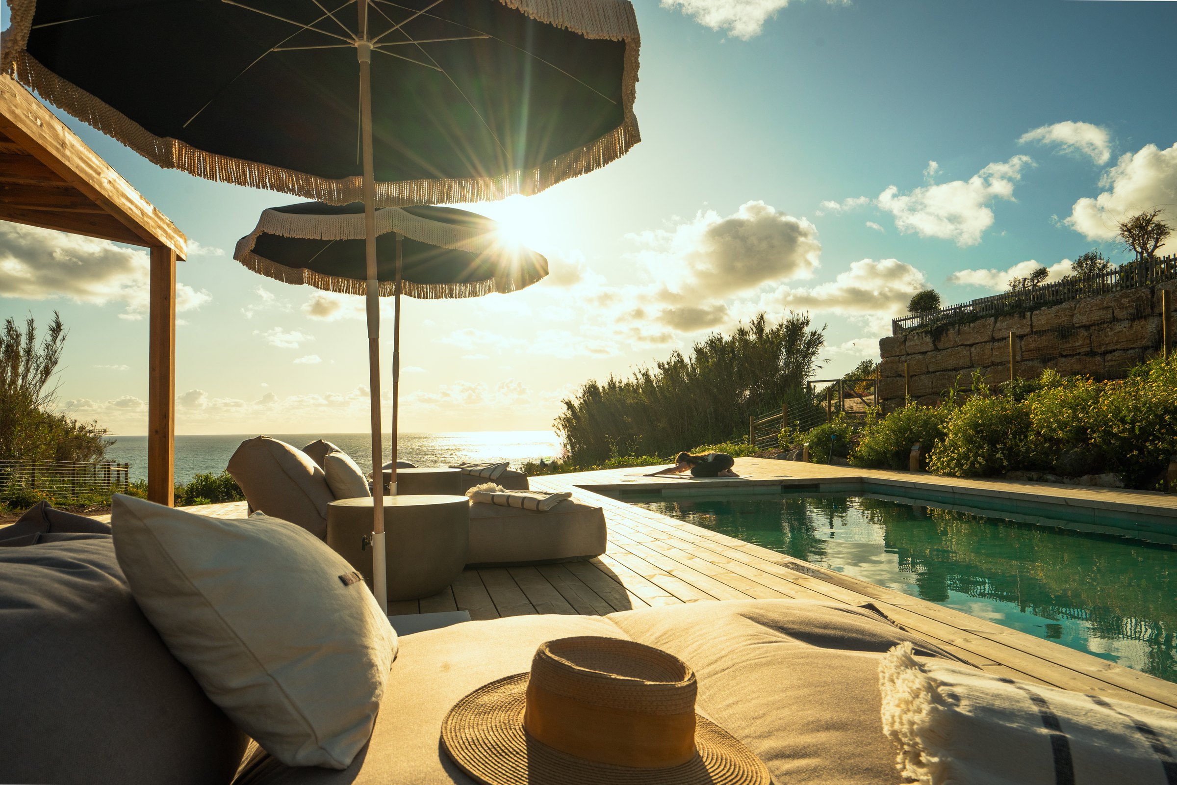 The clifftop pool and loungers at sunset above the ocean