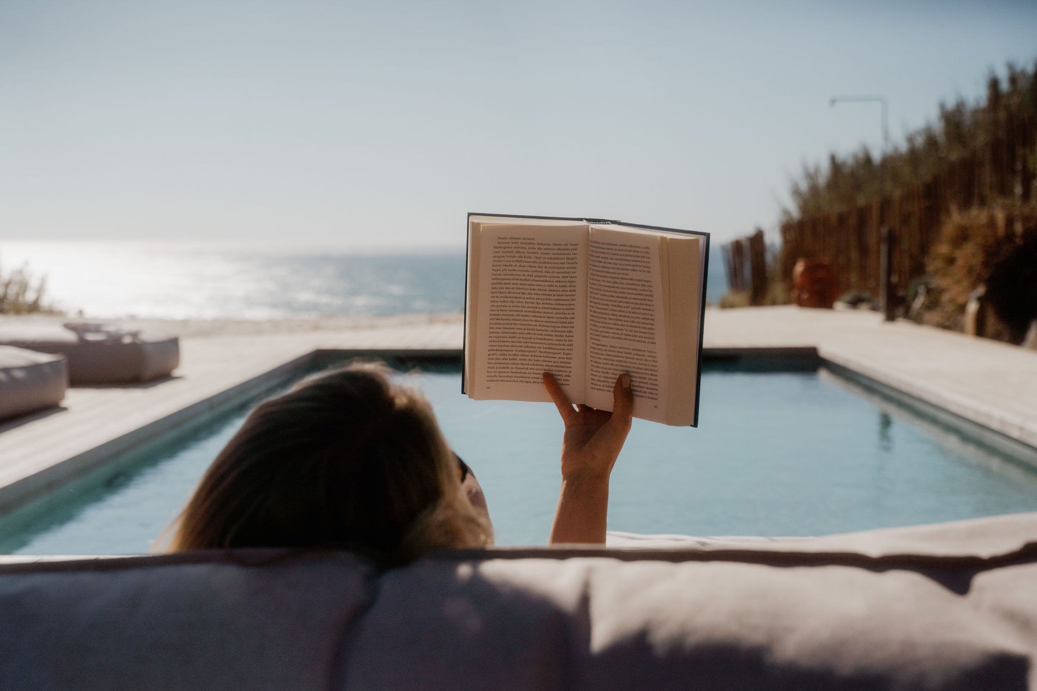 Reading a book beside the pool overlooking the water