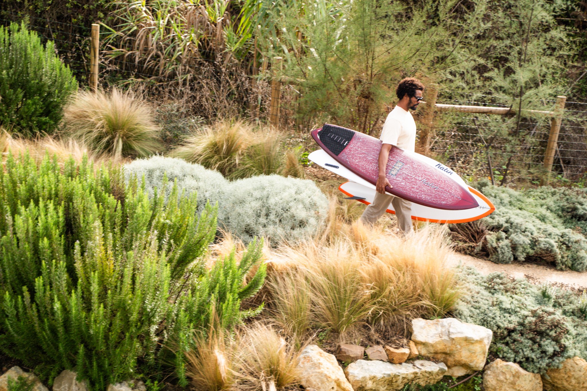 Carrying a surfboard through the coastal scrub