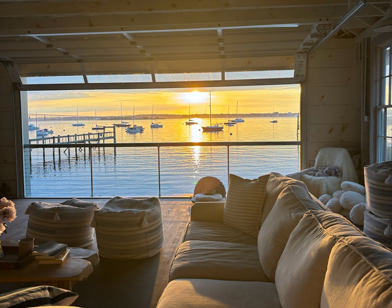 Boathouse lounge with floor cushions looking out over moored boats at sunset