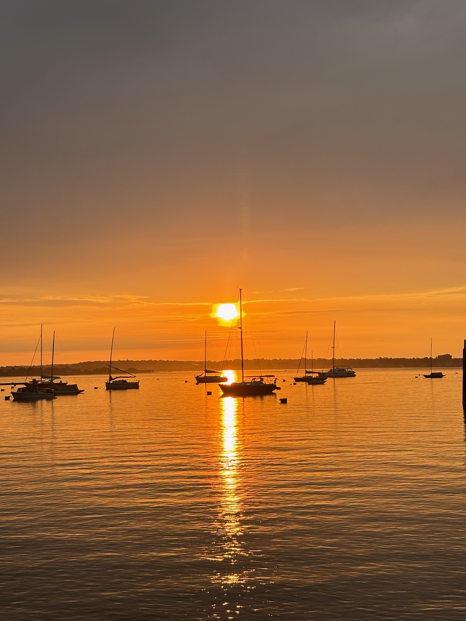Sun setting over the harbour with sailing boats at anchor