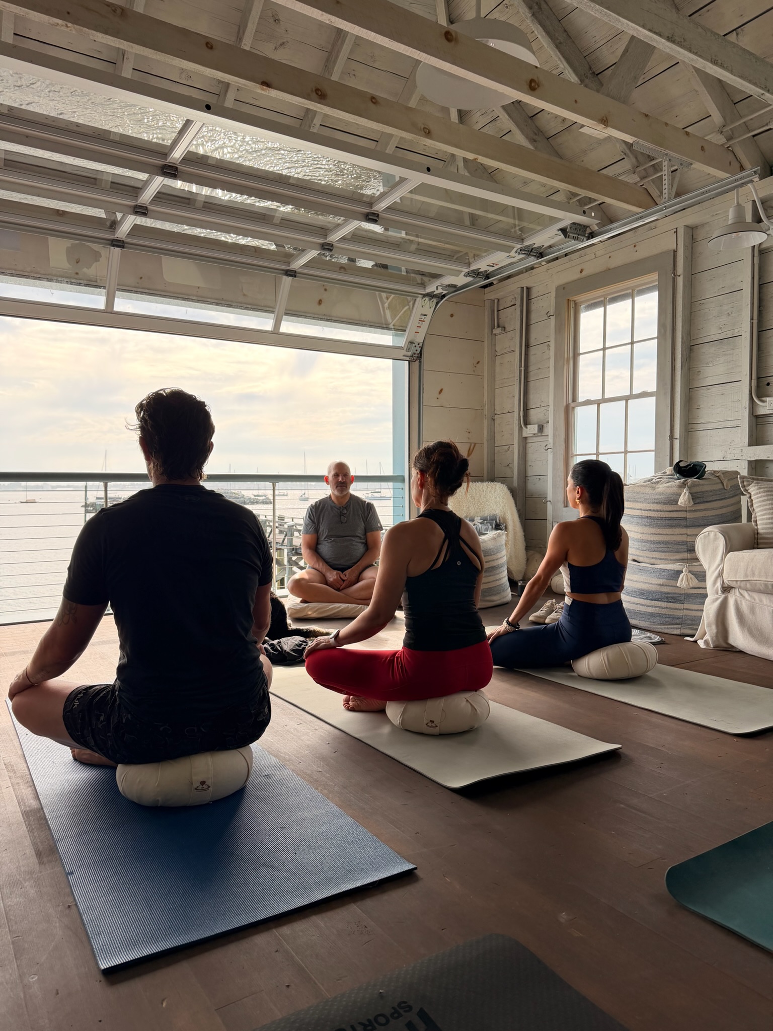 Morning meditation on mats in a light-filled boathouse