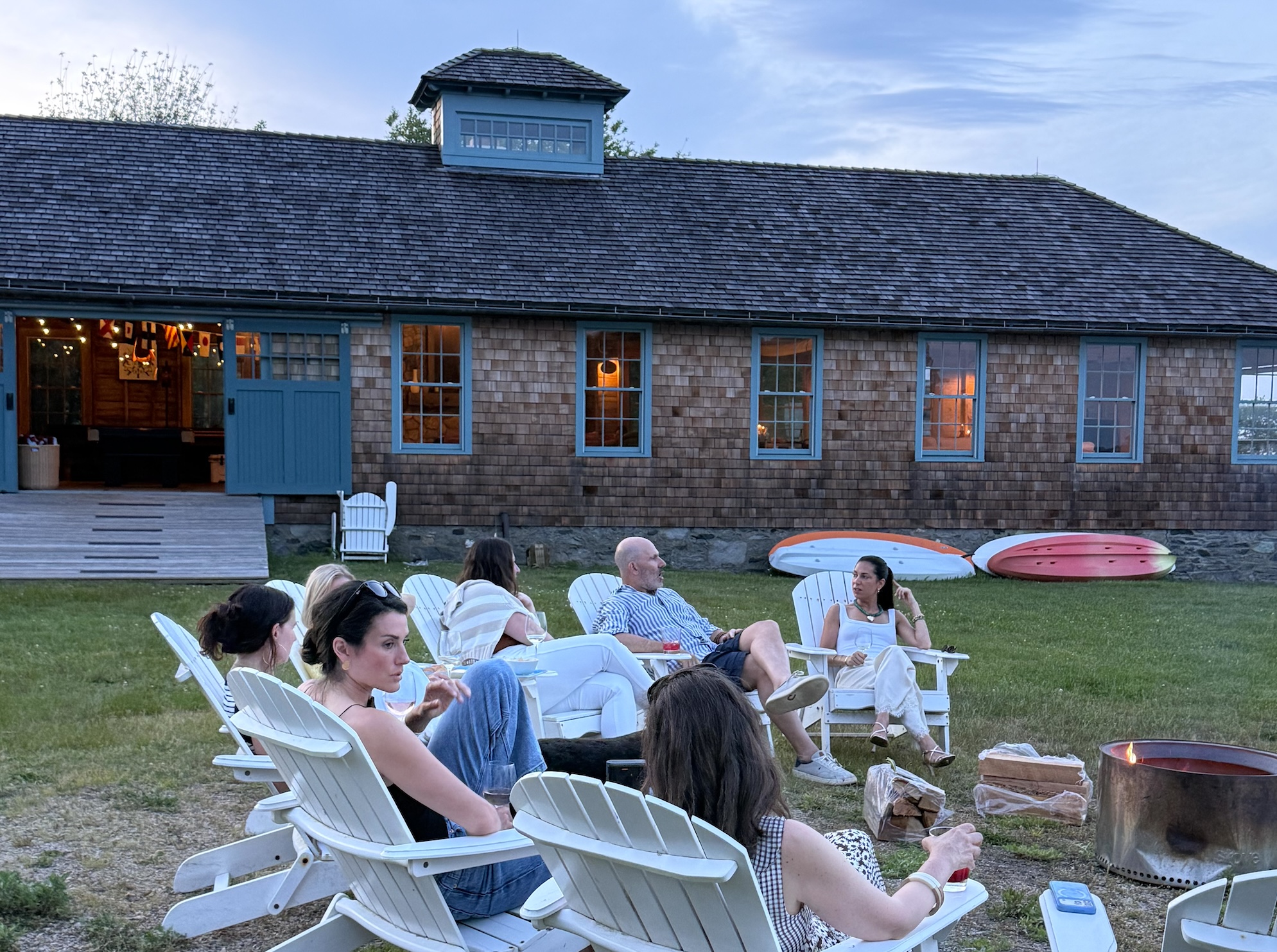 Participants in a circle of chairs on the lawn at dusk