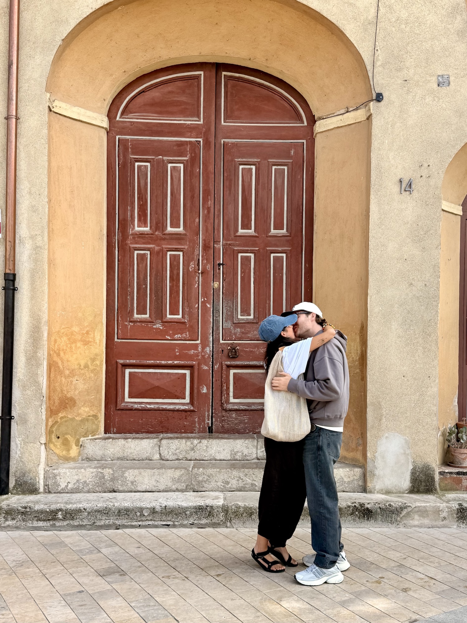Two people embracing in front of a weathered red door