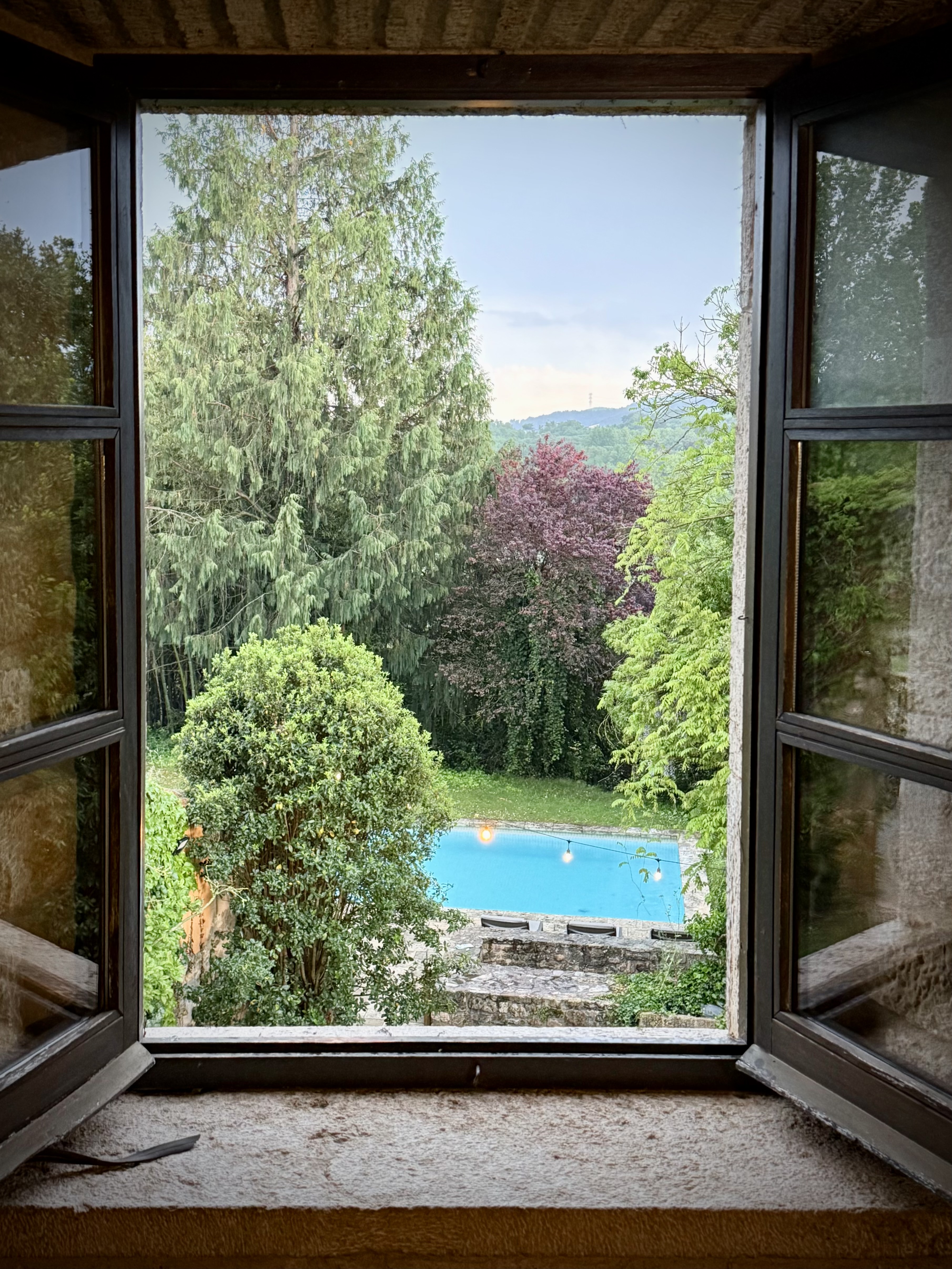 View through an open window to the garden and pool below