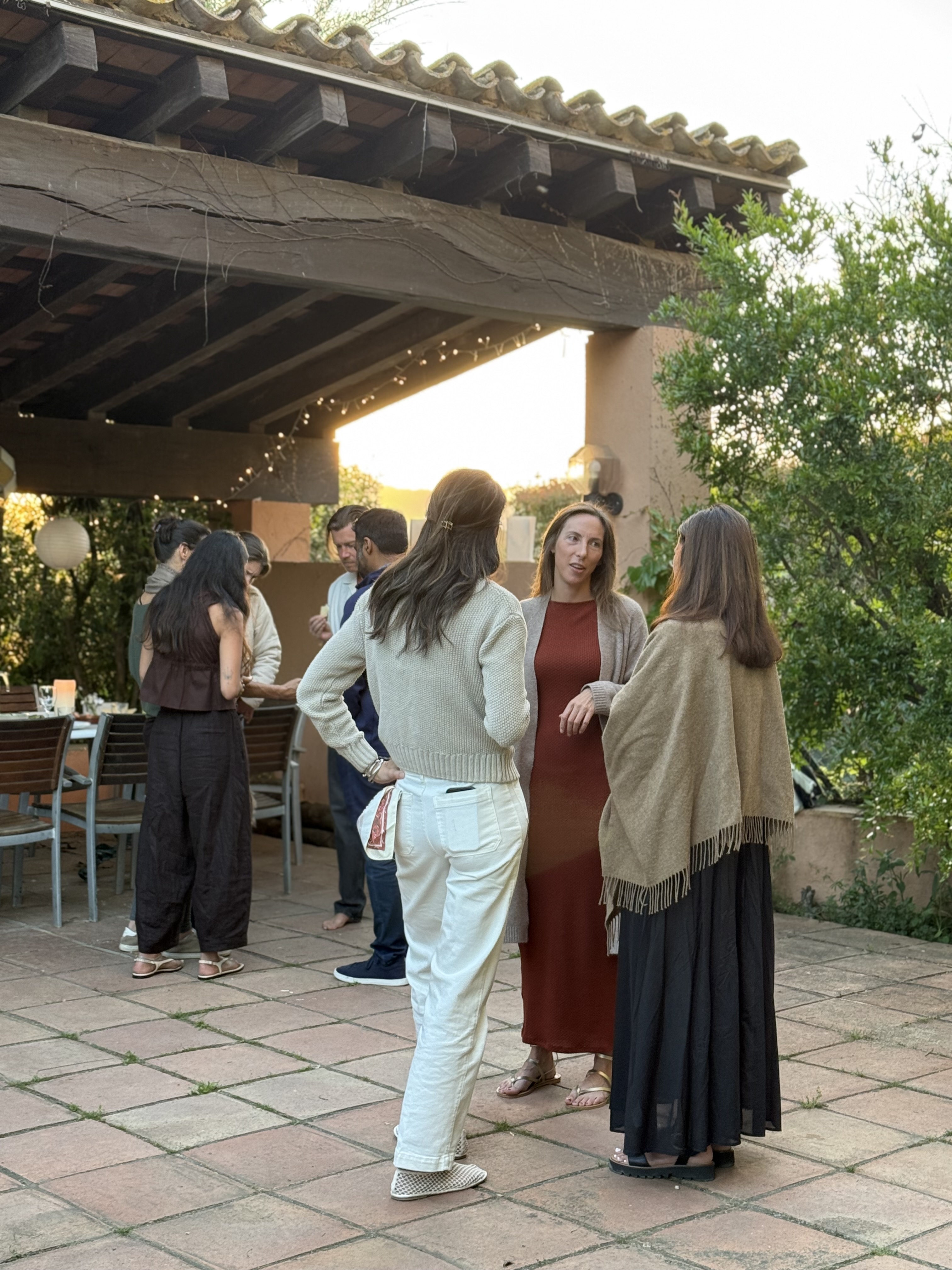 Participants talking under a covered terrace before dinner
