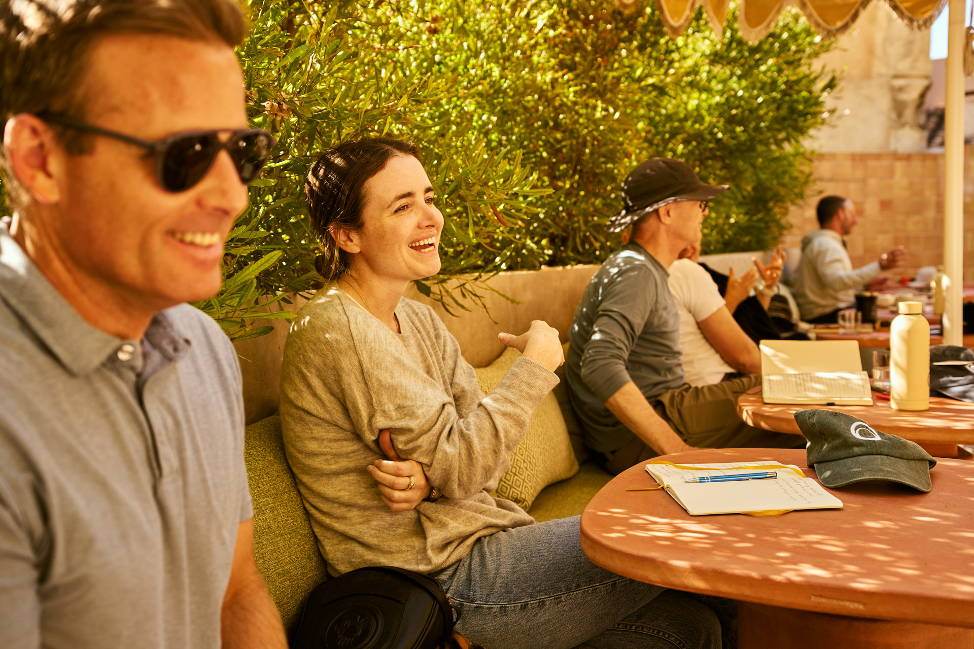 Participants talking around an outdoor table in dappled sunlight