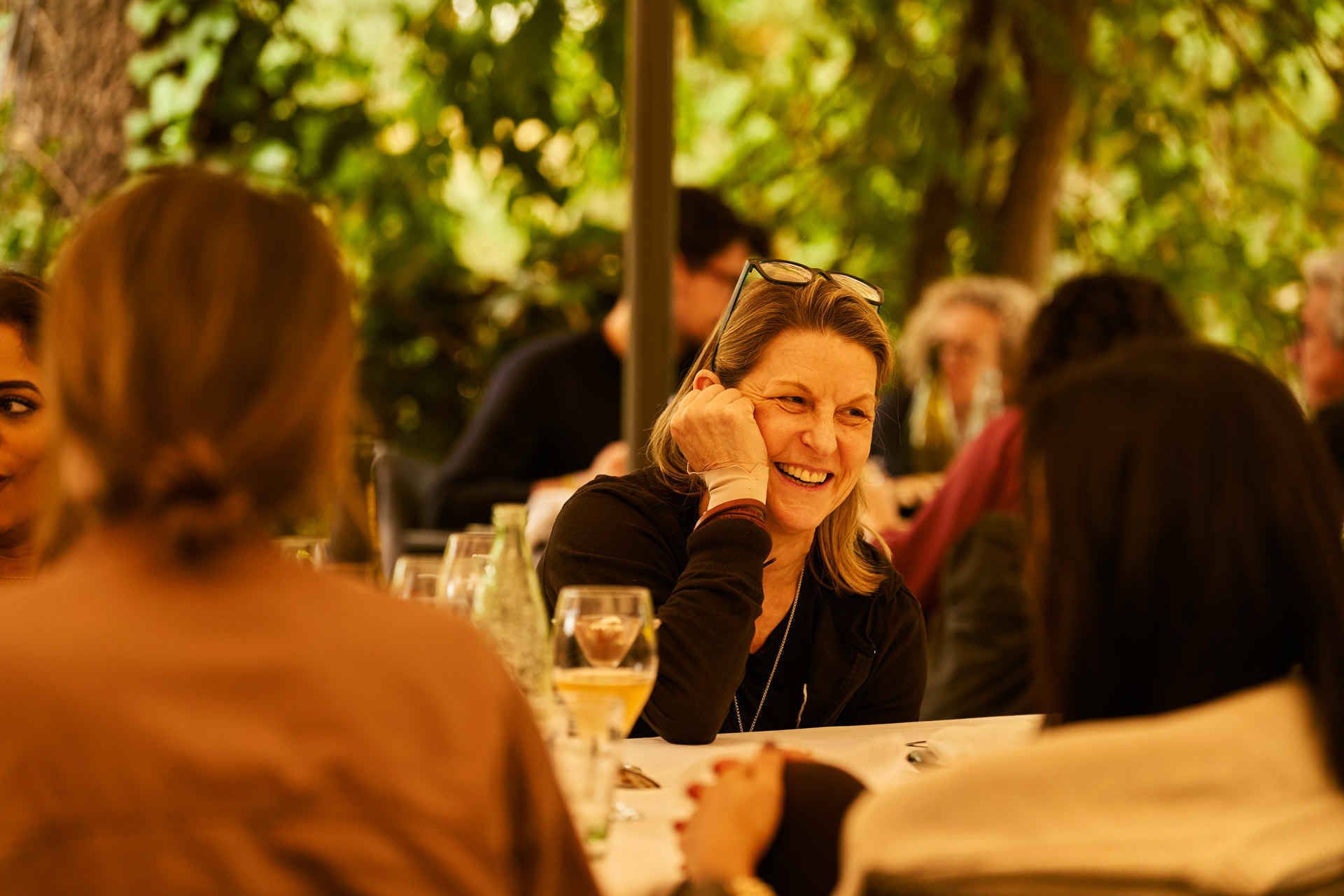 Group seated at an outdoor table over wine, mid-conversation