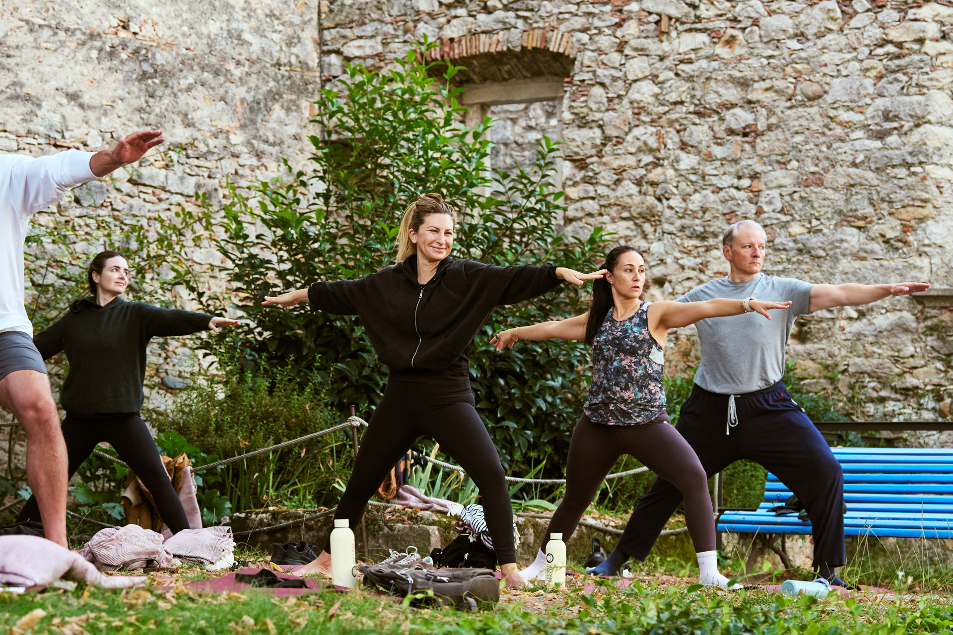 Outdoor yoga session on mats beside an old stone wall