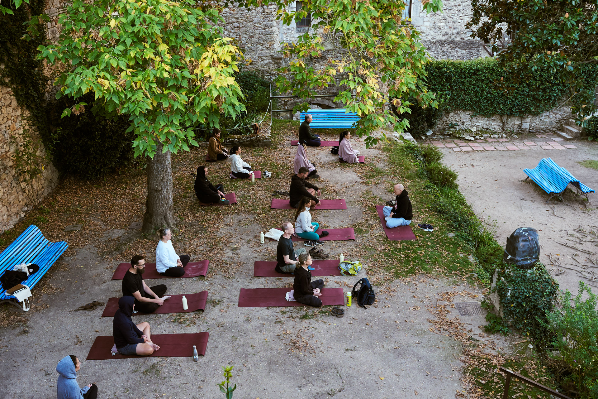 Group practising and resting on mats in a walled garden