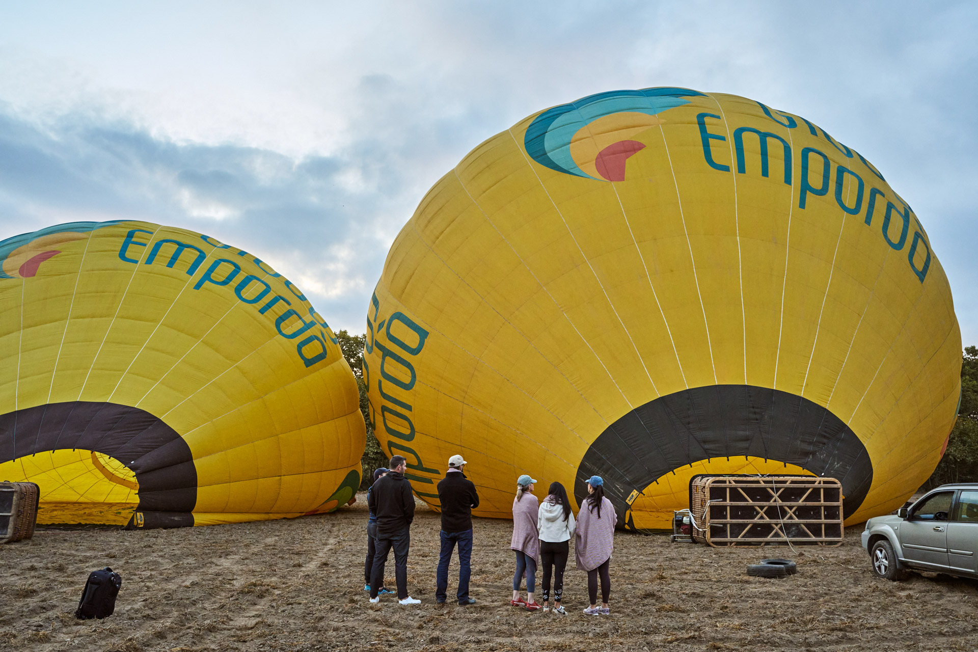 Hot-air balloons being inflated on the ground at dawn