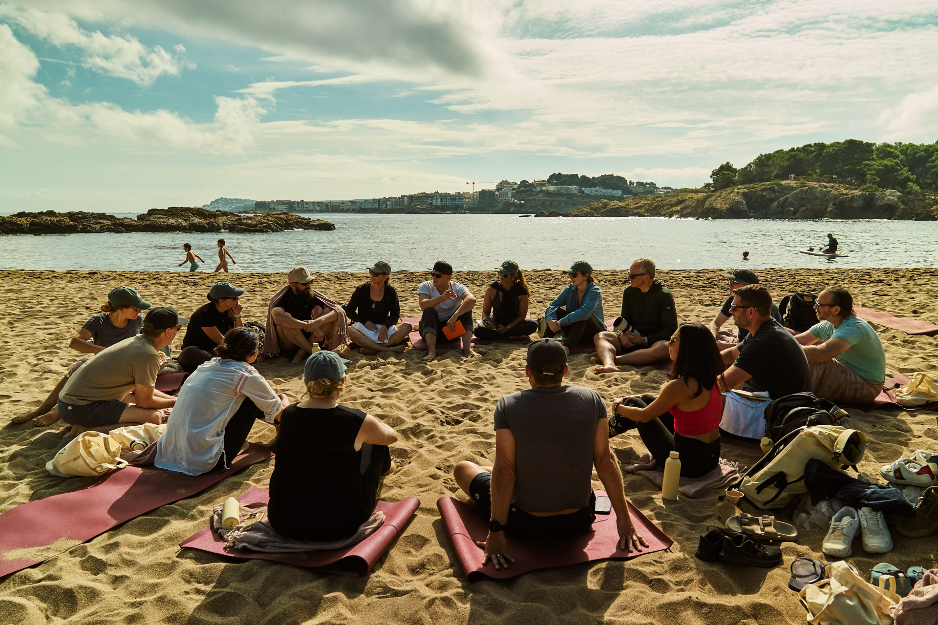 Circle of participants sitting on the sand for a group session