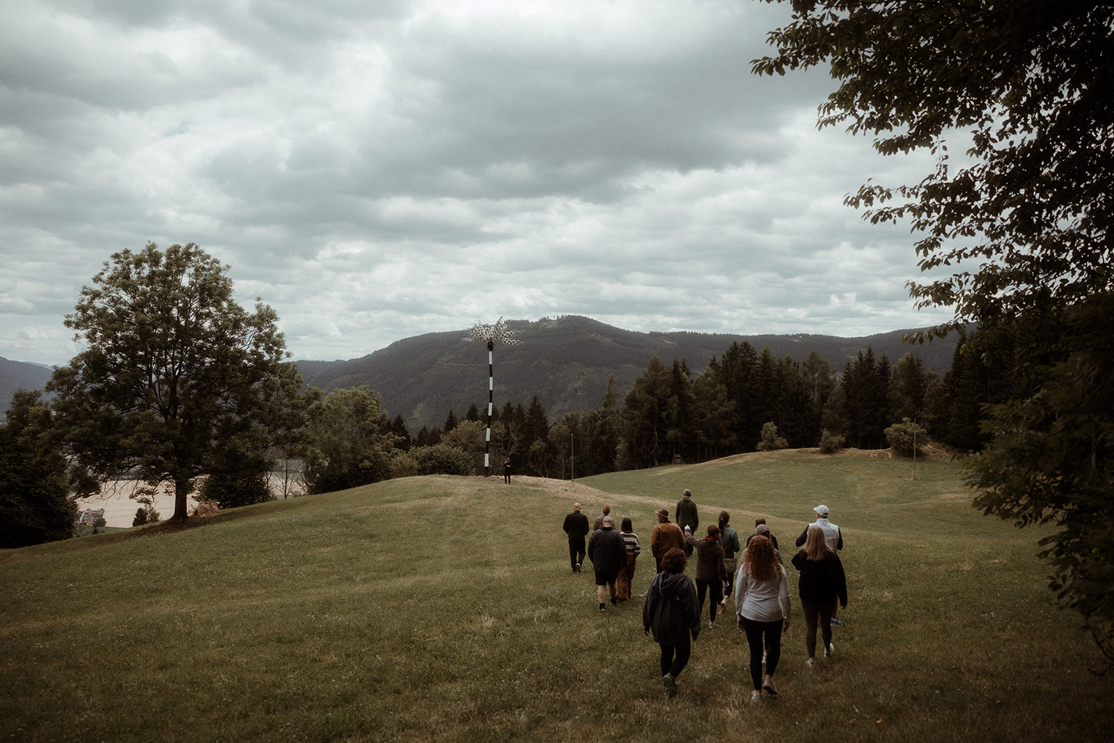 The group walking across an alpine meadow under heavy cloud