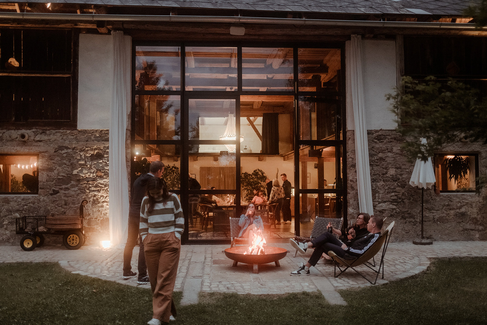 Guests around a fire pit outside the restored farmhouse at night