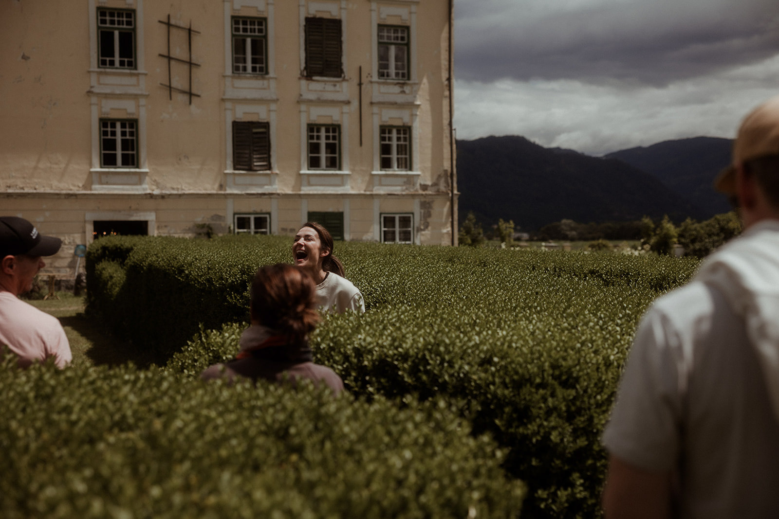 Laughing together beside a hedge below the mountains