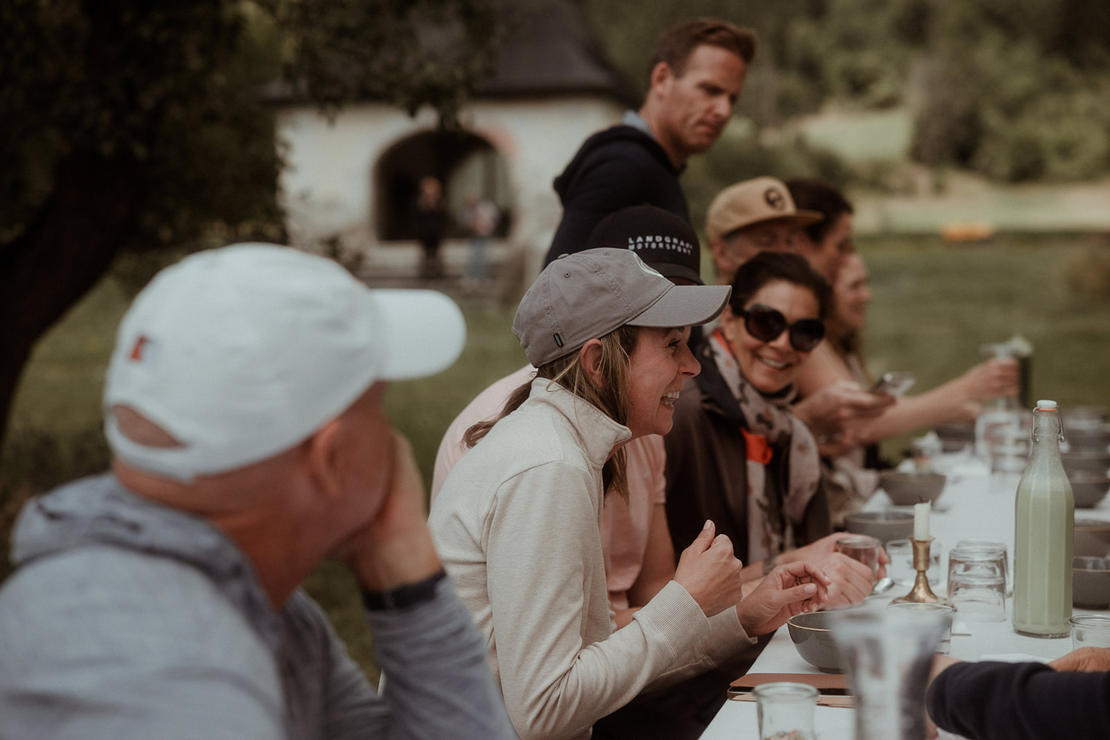 Long lunch table outdoors with guests talking over the meal