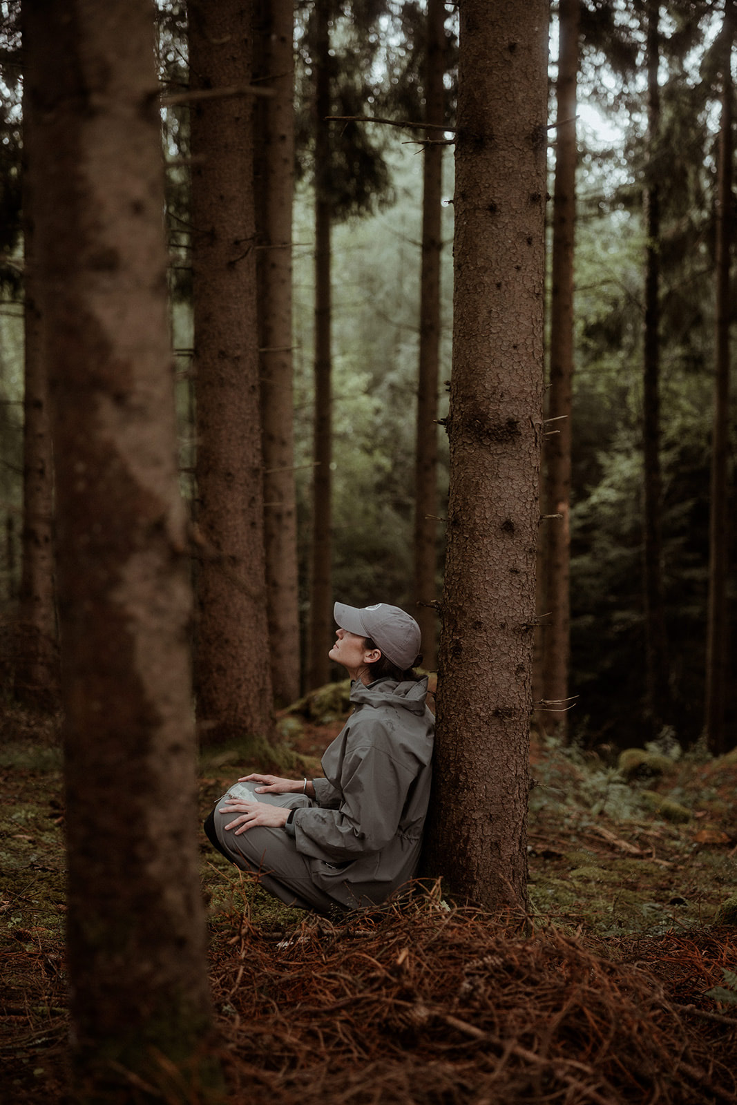 A participant sitting alone among the spruce trees
