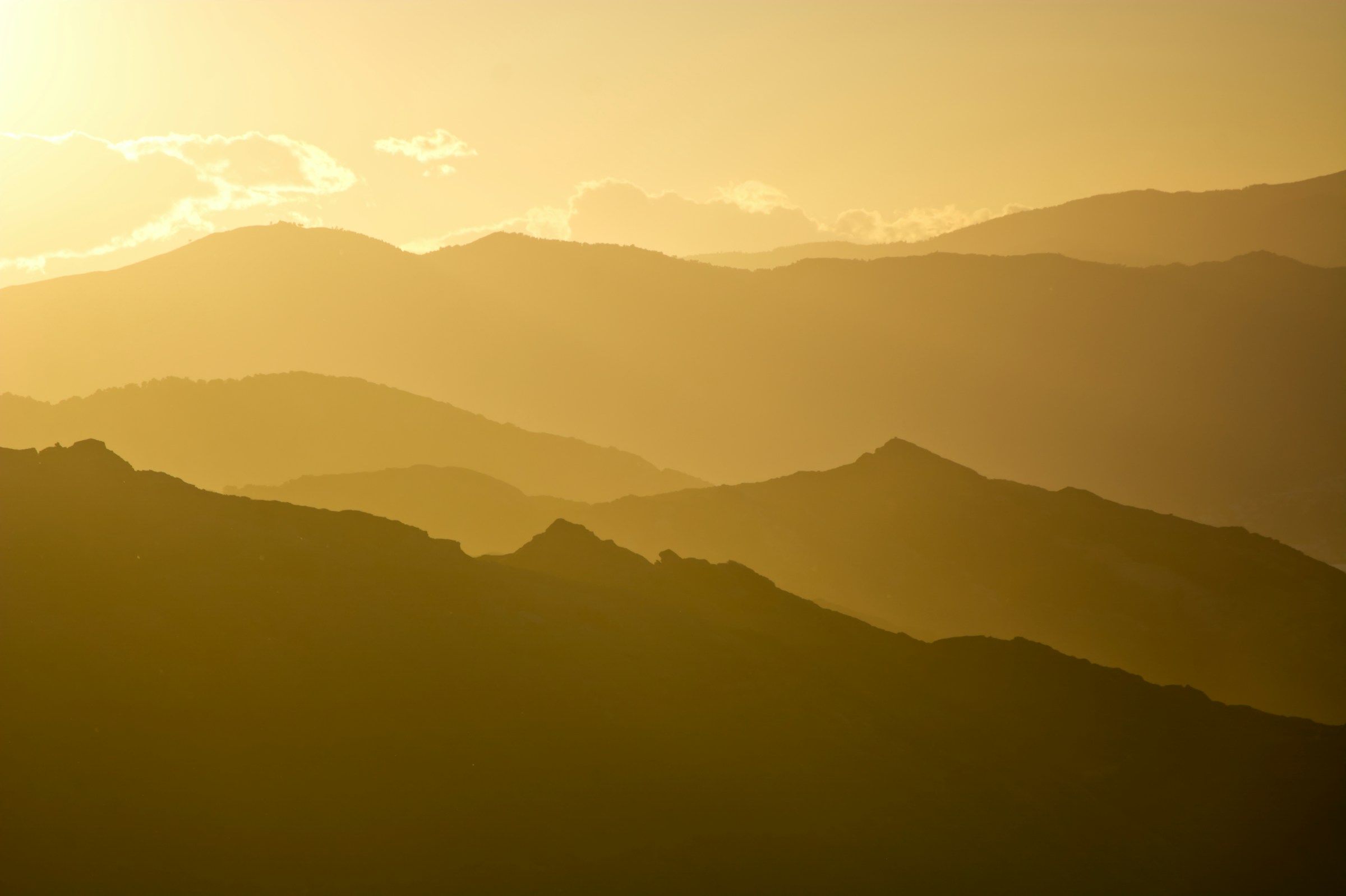 Layers of hills fading into golden haze at sunset