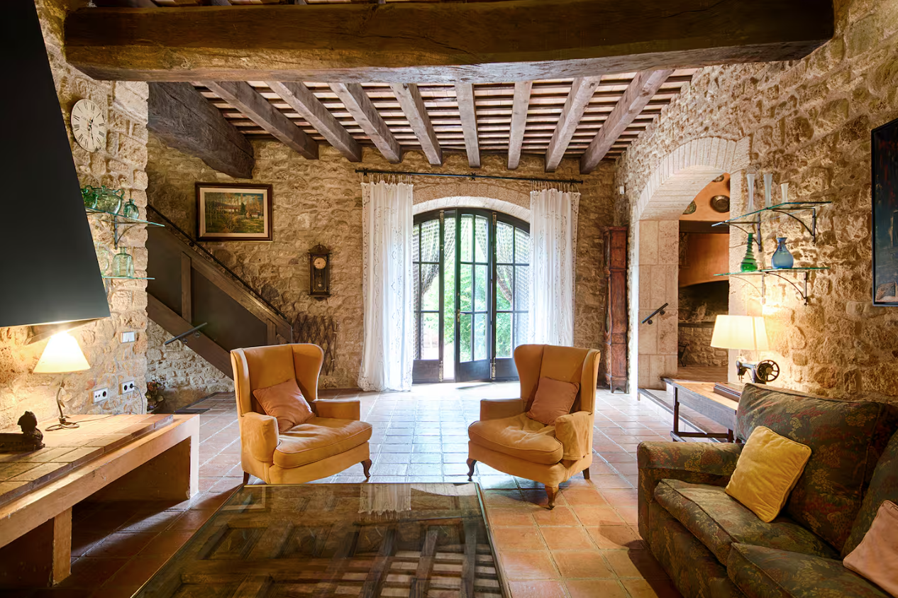 A beamed sitting room with armchairs and a fireplace
