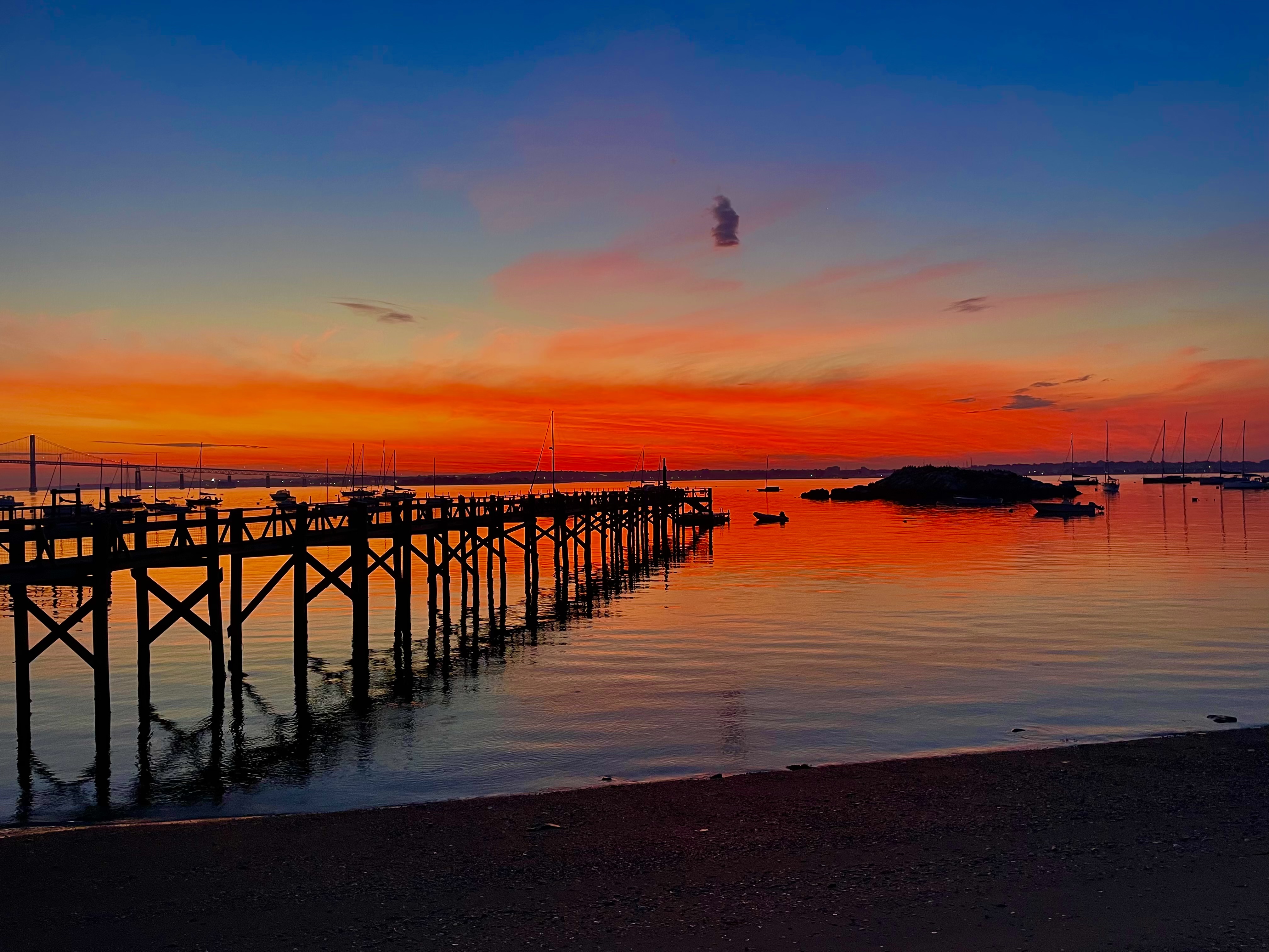 A vivid red sunset over the pier and bay