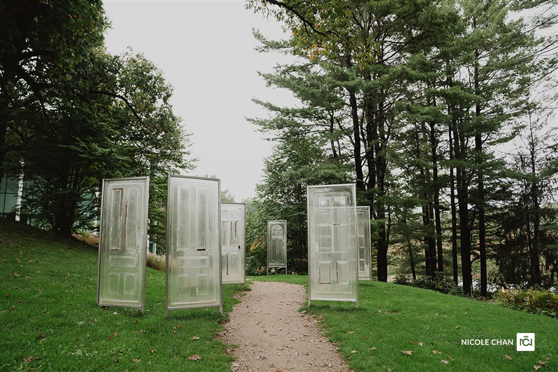 Glass door sculptures on a lawn among tall trees