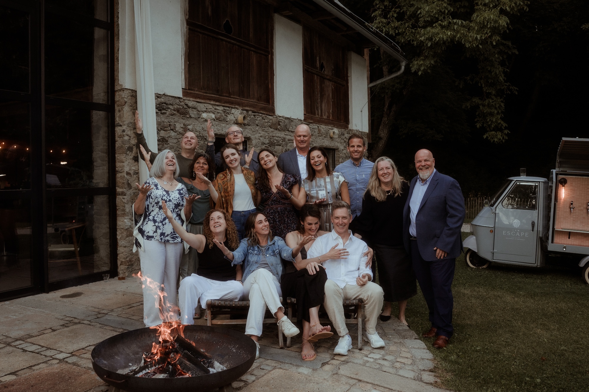 Group photo beside a fire pit outside a stone building at night