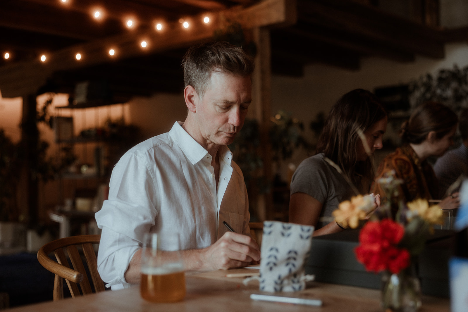 Guests talking across a table set with flowers and candles