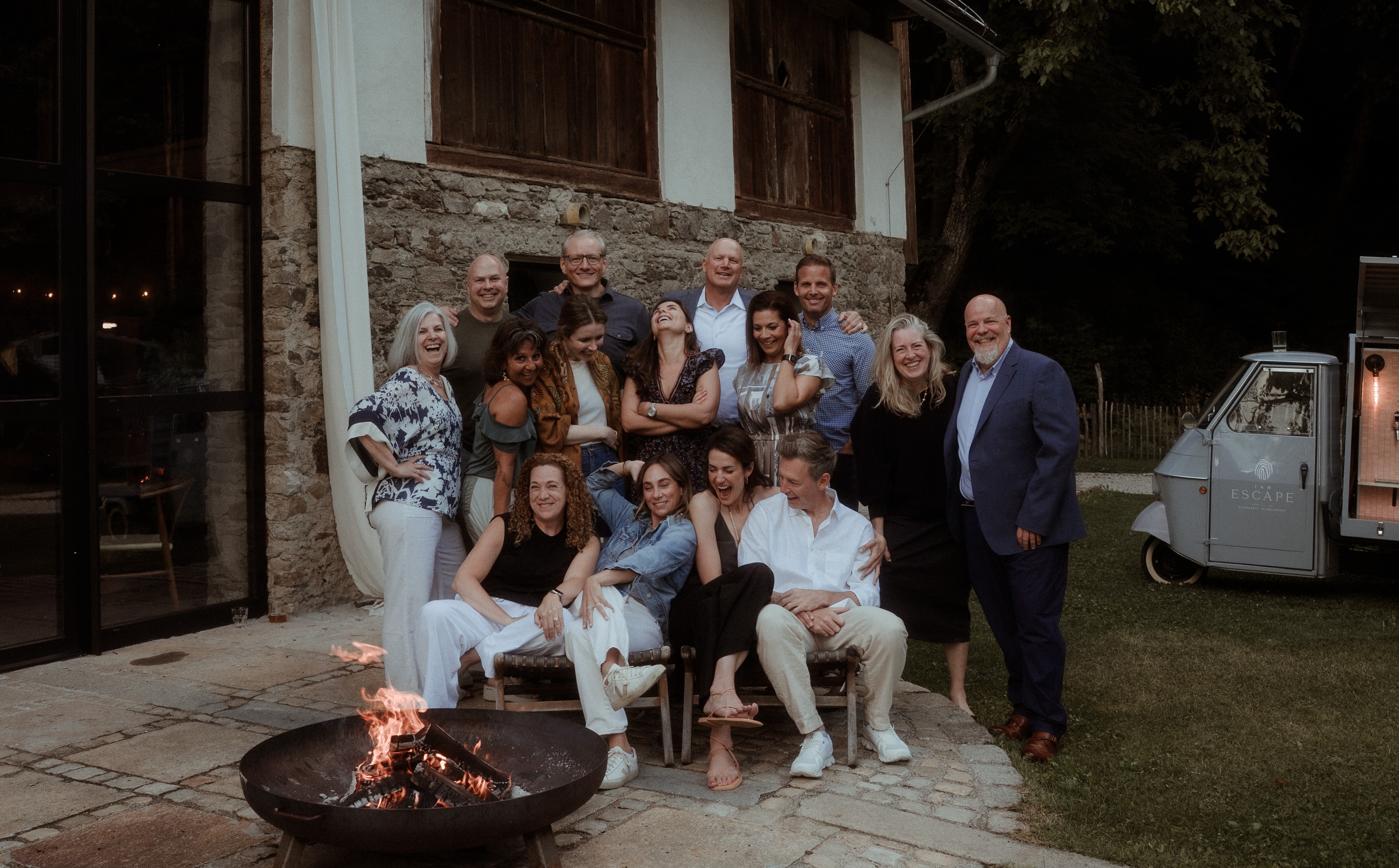 Group photo beside a fire pit outside a stone building at night