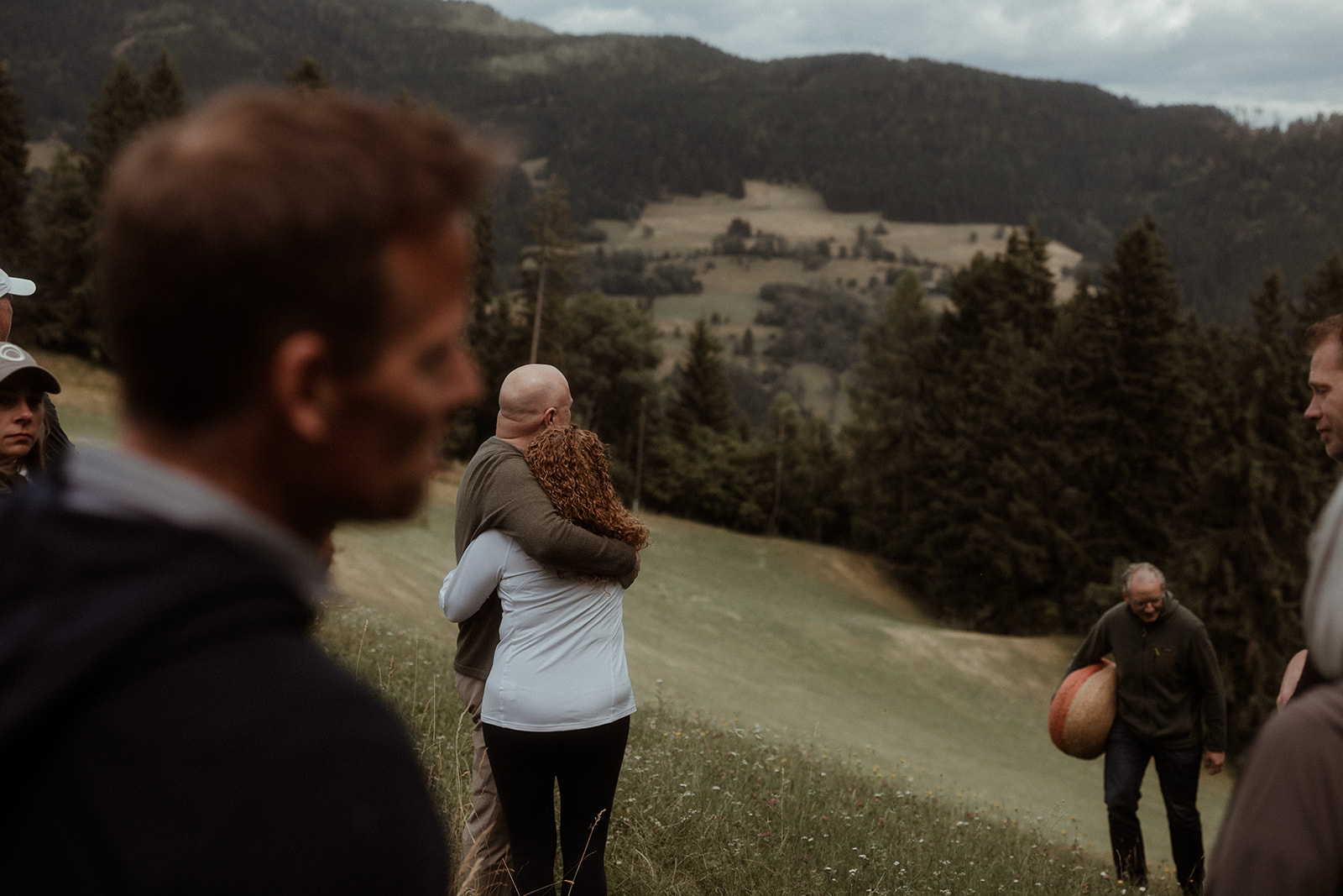 Two people embracing on a hillside above the valley