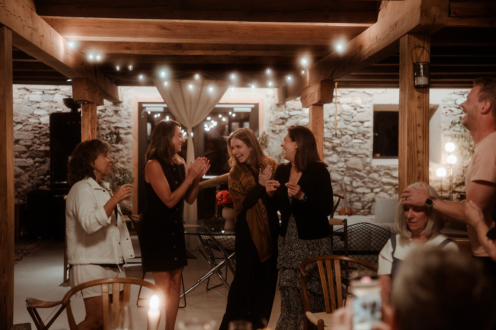 Guests talking under string lights on a terrace